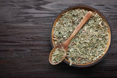 Bowl with aromatic dried lemongrass and spoon on wooden table, top view. Space for text