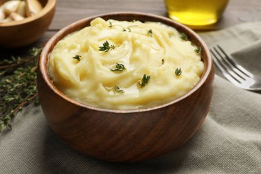 Bowl of delicious mashed potato with thyme on grey tablecloth, closeup