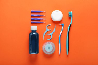 Flat lay composition with dental floss and different teeth care products on orange background