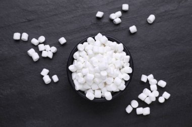 Bowl with delicious marshmallows on black background, flat lay