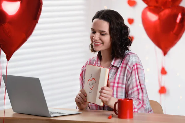 Valentine\'s day celebration in long distance relationship. Woman having video chat with her boyfriend via laptop indoors