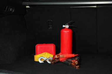 Red fire extinguisher, battery jumper cables, towing strap and first aid kit in trunk. Car safety