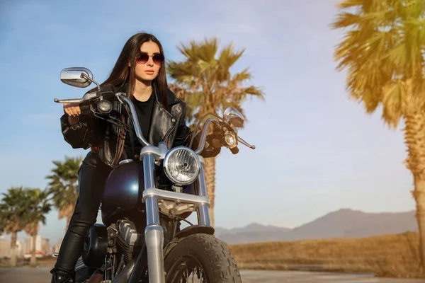 Beautiful young woman riding motorcycle on sunny day