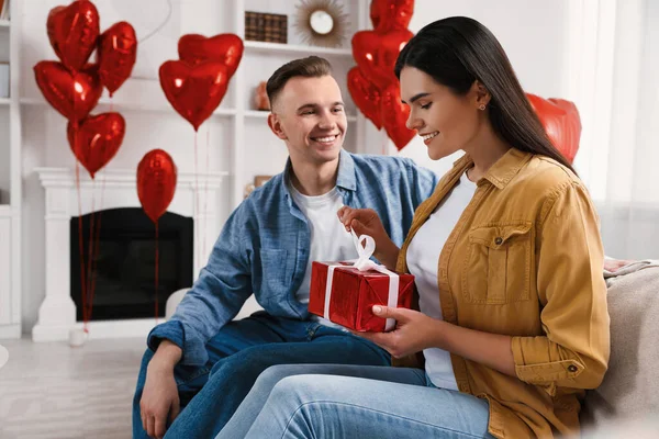 Woman opening gift from her boyfriend indoors. Valentine\'s day celebration