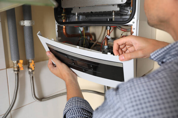 Man opening top of gas boiler indoors, closeup