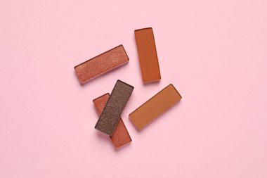 Different beautiful eye shadows on pink background, flat lay