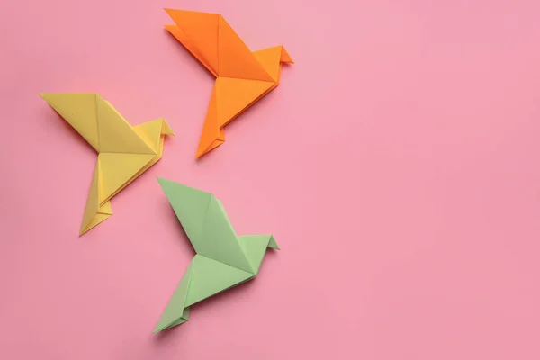 Beautiful colorful origami birds on pink background, flat lay. Space for text