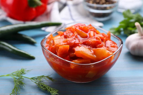 Bowl of delicious lecho on light blue wooden table, closeup