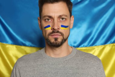 Man with face paint near Ukrainian flag