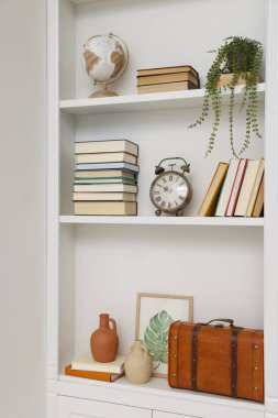 Books and different decorative elements on shelving unit indoors