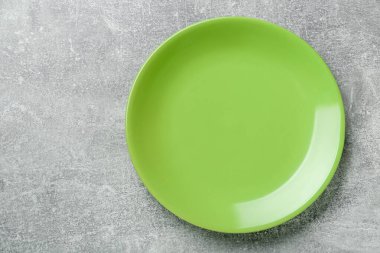 Empty green ceramic plate on light grey table, top view. Space for text