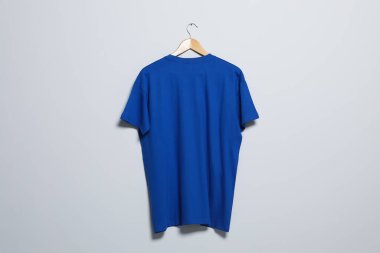 Işık duvarında mavi tişörtlü bir askı. Tasarım için model