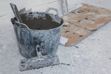 Bucket with cement and putty knifes indoors. Home improvement