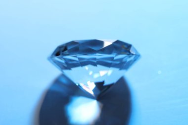 Beautiful dazzling diamond on blue background, closeup