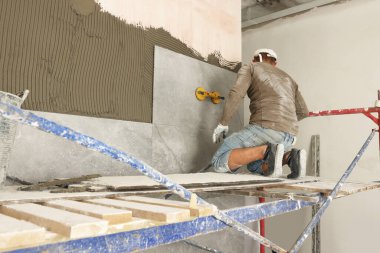 Worker installing new wall tile in room. Prepared for renovation