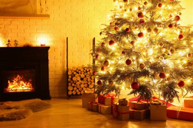 Beautiful Christmas tree and gifts near fireplace in room. Interior design