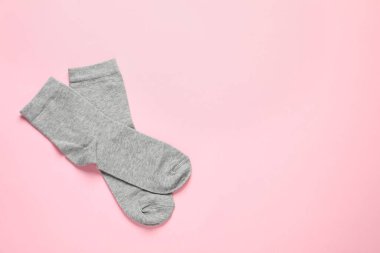 Pair of grey socks on pink background, flat lay. Space for text