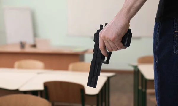 School shooting. Man with gun in classroom, closeup