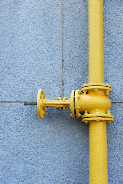 Yellow gas pipe on grey wall outdoors