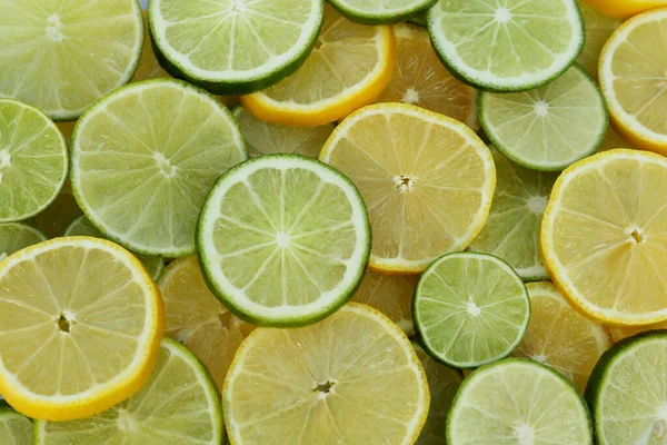 Fresh ripe lemons and limes as background, top view
