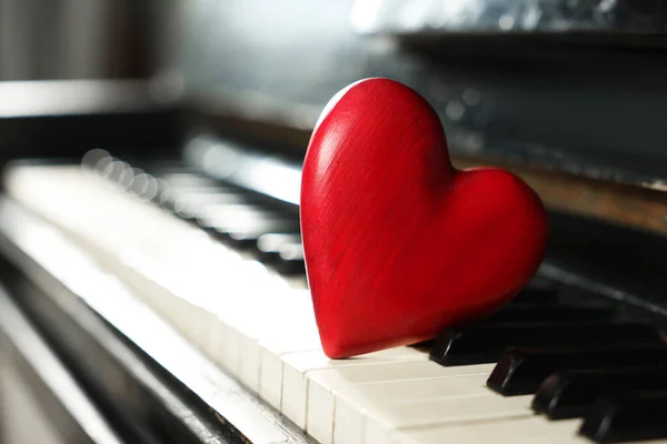 Red decorative heart on piano keys, closeup. Space for text