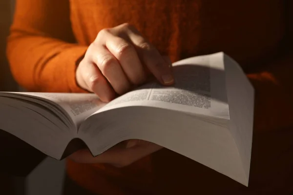 Woman reading Bible against black background, closeup