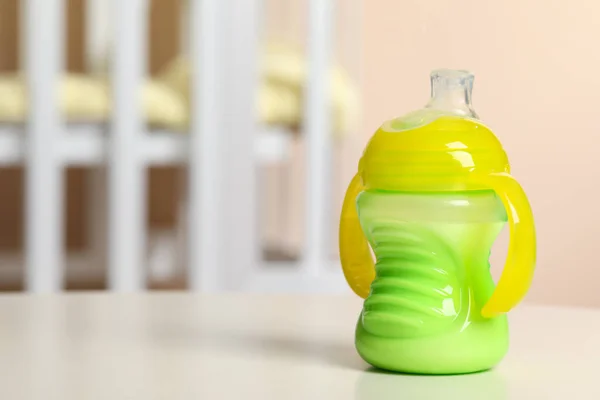 Feeding bottle with milk on white table indoors. Space for text