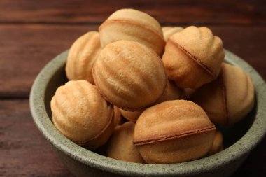 Delicious nut shaped cookies with boiled condensed milk in bowl on wooden table, closeup