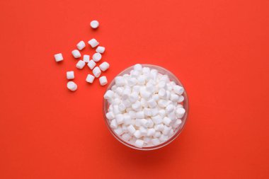 Bowl with delicious marshmallows on red background, flat lay