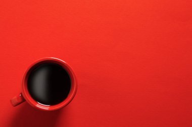 Cup with aromatic coffee on red background, top view. Space for text