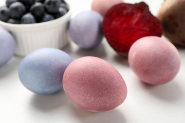 Colorful Easter eggs painted with natural dyes on white table, closeup