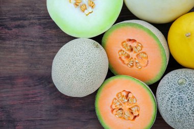 Different types of tasty ripe melons on wooden table, flat lay