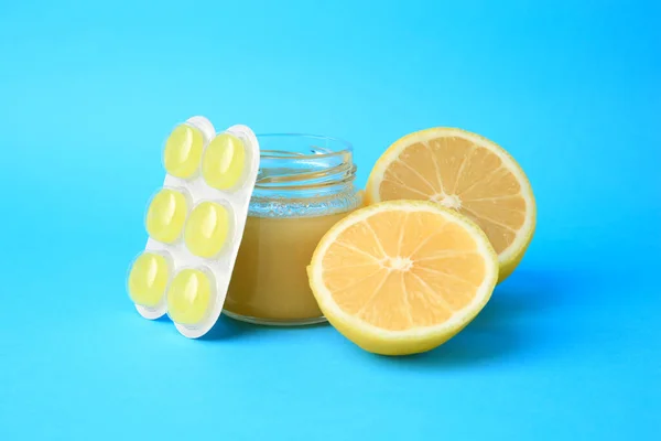 Blister with cough drops, fresh lemon and honey on light blue background