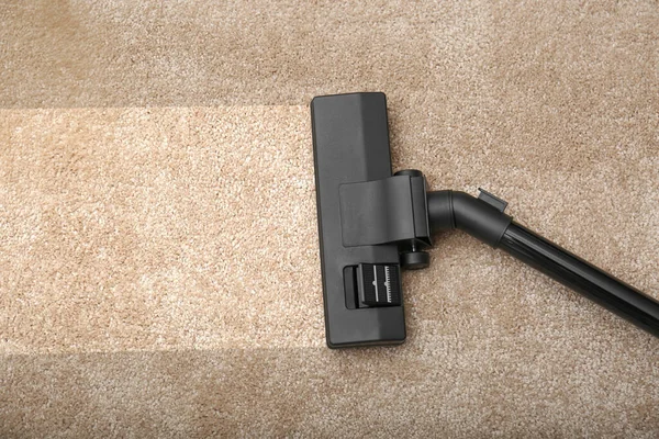 Vacuuming dirty beige carpet. Clean area after using device, top view