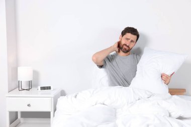 Man with soft pillow on bed at home