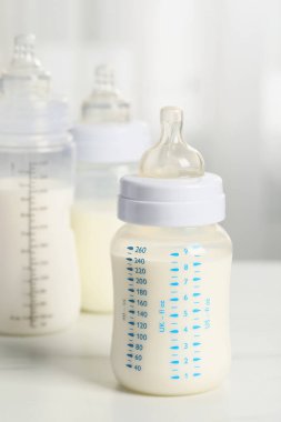 Feeding bottles with milk on white table indoors