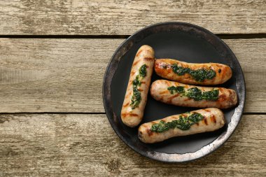 Tasty fresh grilled sausages with sauce on wooden table, top view. Space for text