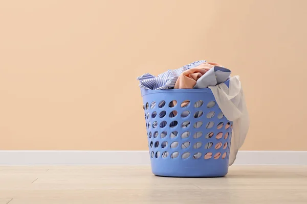 Laundry basket with clothes near beige wall indoors. Space for text