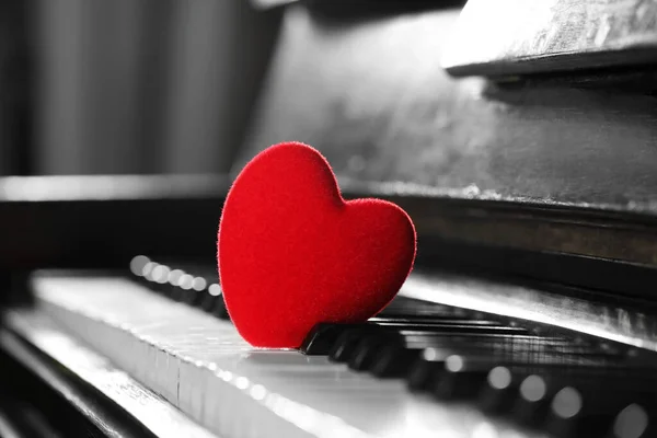 Small red decorative heart on piano keys, closeup. Space for text