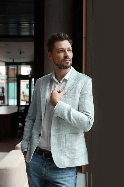Attractive serious man wearing jacket in hall