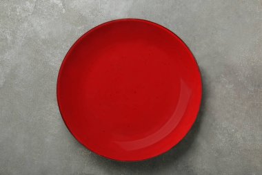 Empty burgundy ceramic plate on grey table, top view
