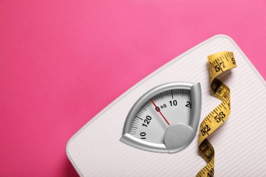 Weight loss concept. Scales and measuring tape on pink background, top view. Space for text clipart