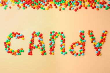 Word Candy made of tasty sweets on beige background, flat lay