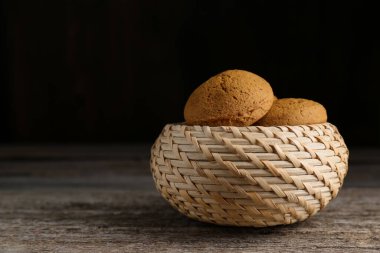 Wicker basket with delicious oatmeal cookies on wooden table. Space for text