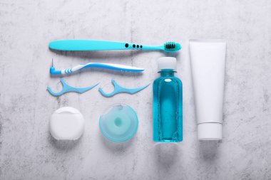 Flat lay composition with dental floss and different teeth care products on light grey textured table