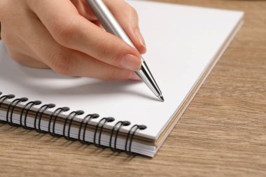 Ahşap masada deftere yazan kadın, yakın plan.