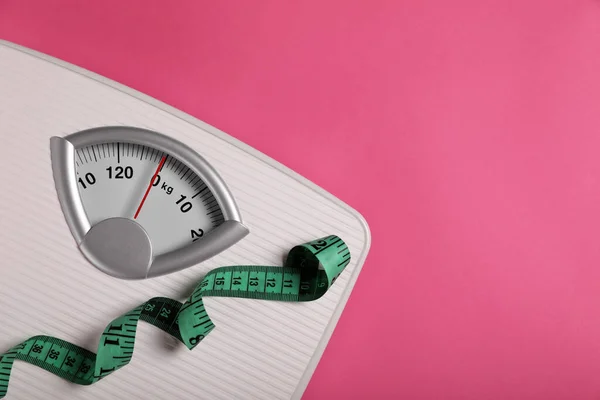 Weight loss concept. Scales and measuring tape on pink background, top view. Space for text