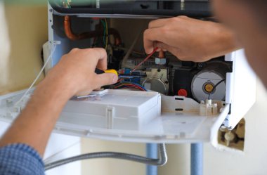 Man repairing gas boiler with screwdriver, closeup