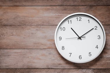 Stylish round clock on wooden table, top view with space for text. Interior element