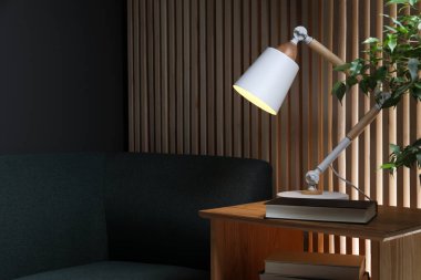 Stylish modern desk lamp and book on wooden cabinet in living room